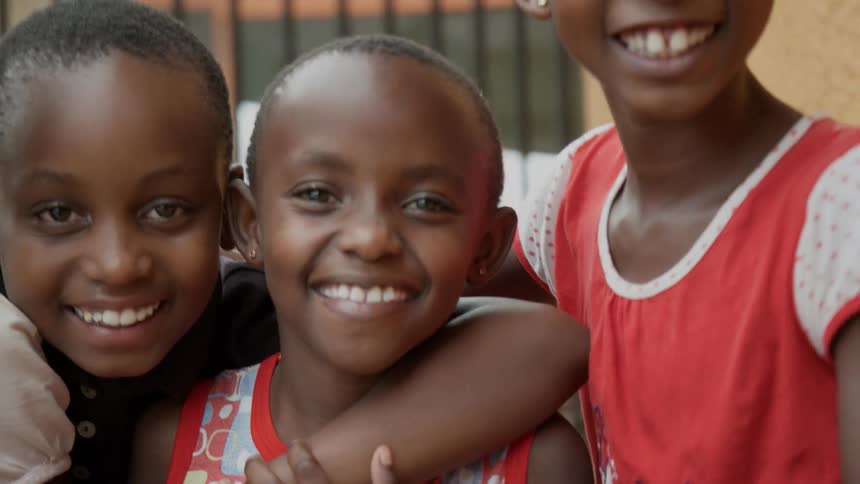 A group of african school children smile and hang on to each other