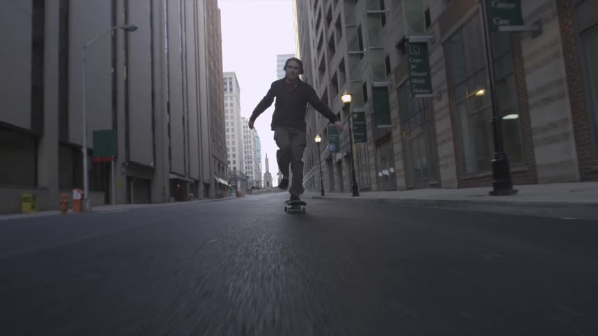 Man skateboards past city buildings