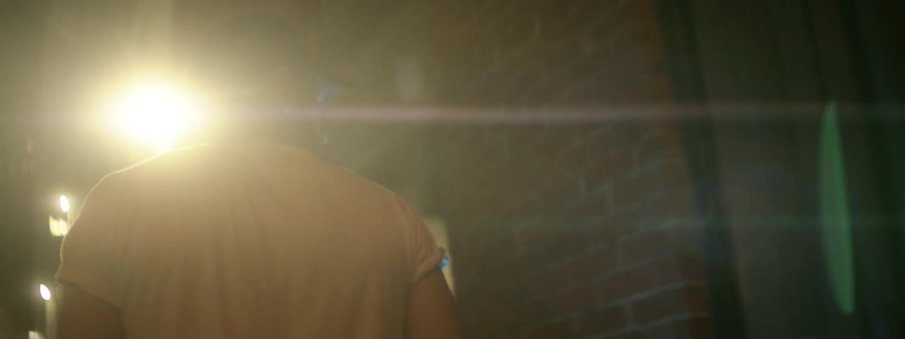 Man walks in dark alley with a glowing light