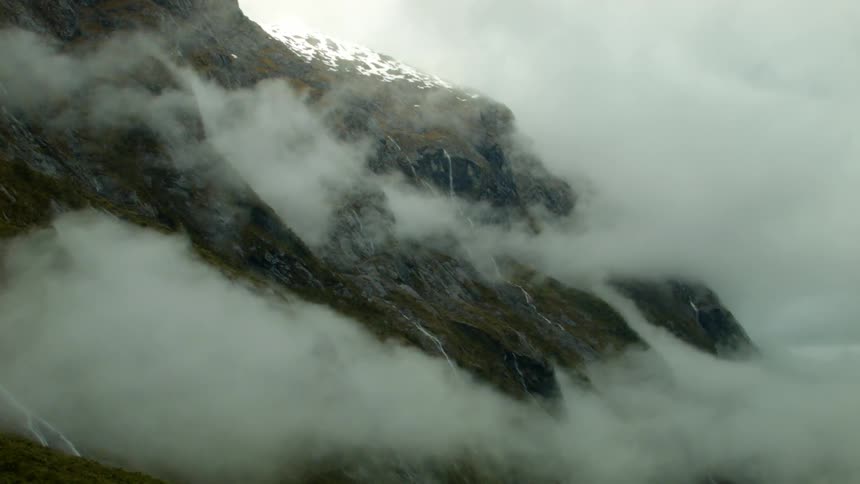 Clouds and fog hang along a mountainside