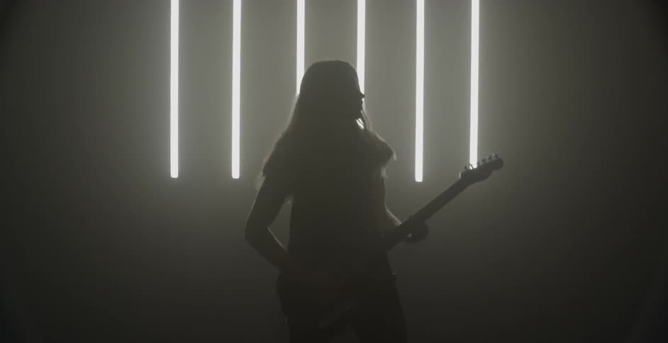 A guitarist plays in a dim room