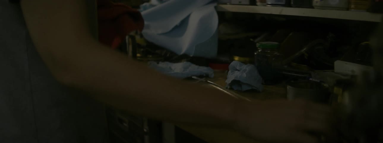 Woman wipes her hands on a rag standing in front of a cluttered desk