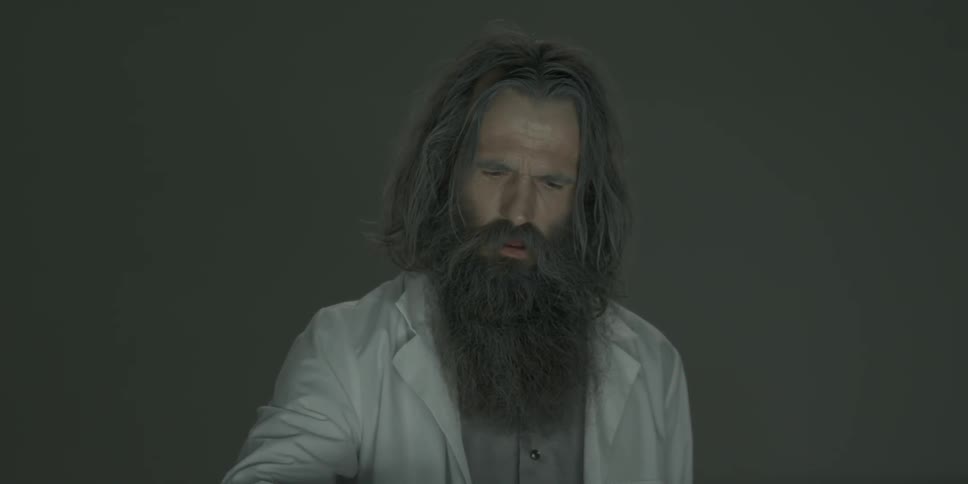 A bearded man lifts his hand out of blue liquid