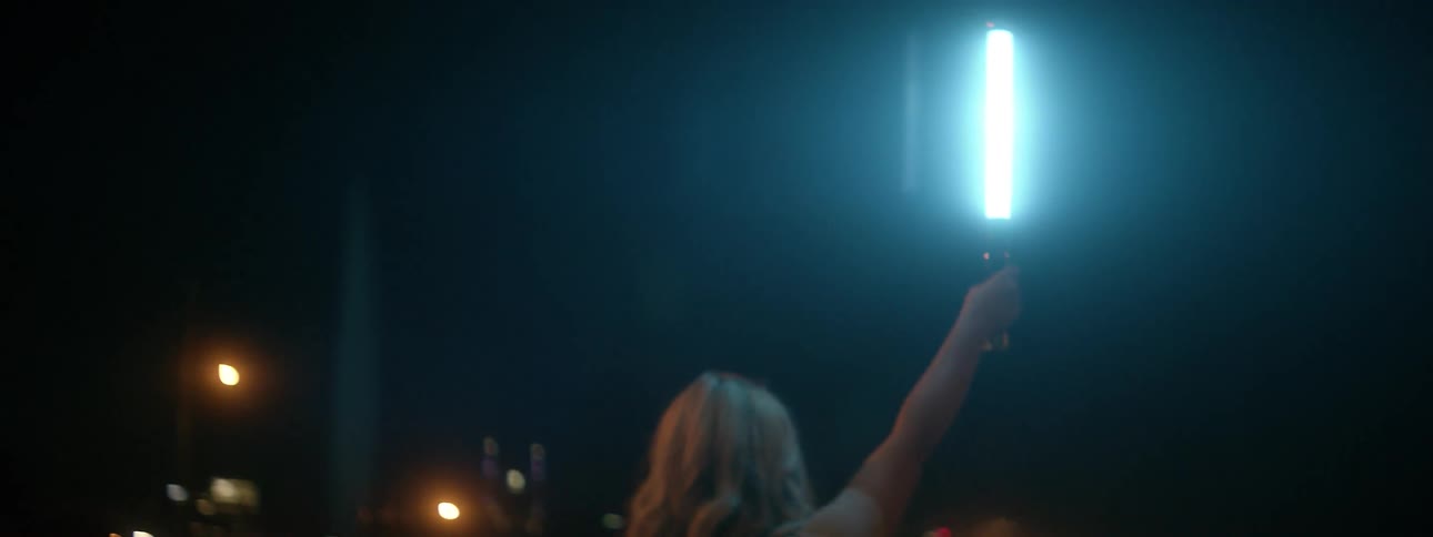 Woman holds up a light in a city at night