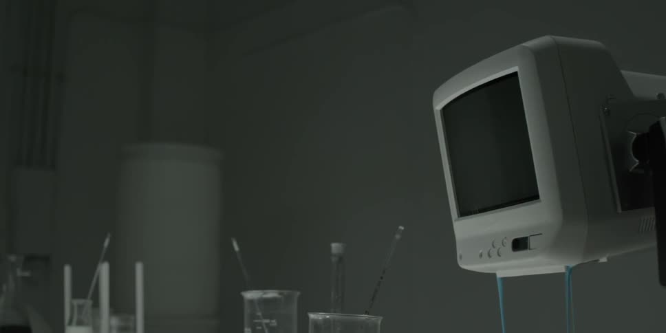 Cylinders and lab implements sit near a monitor dripping blue liquid