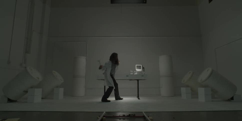A man in a lab coat is swinging a hammer