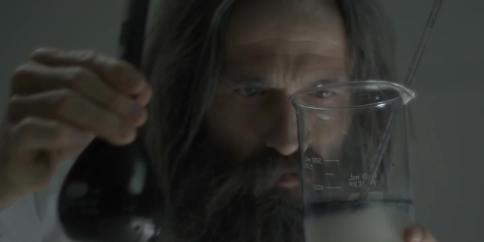 A man mixes liquids in a beaker glass