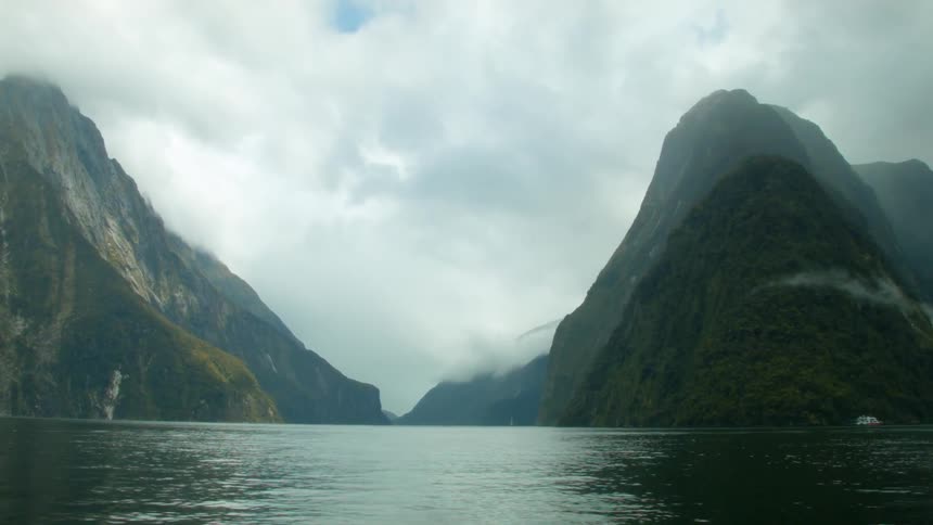 Water flows between two mountains covered with clouds
