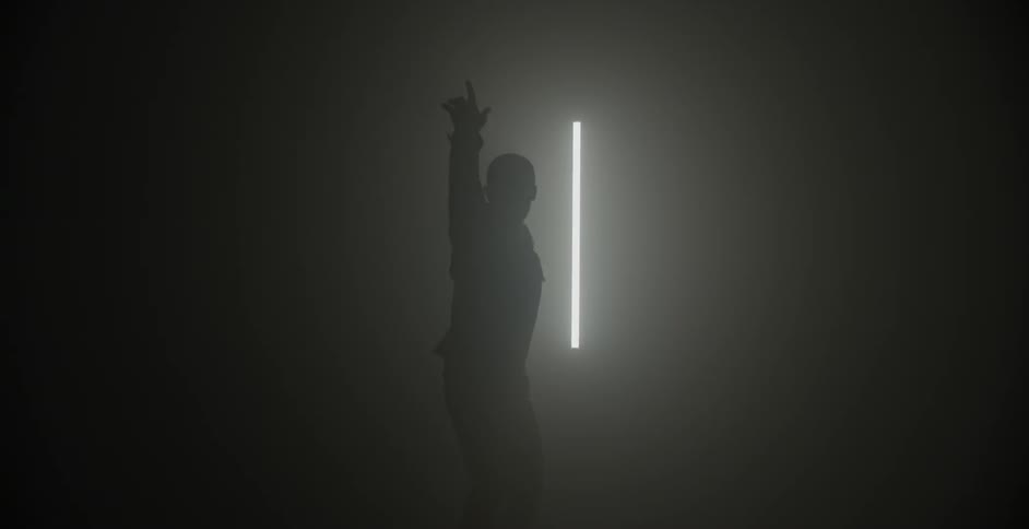 A man gestures and dances in a dim room