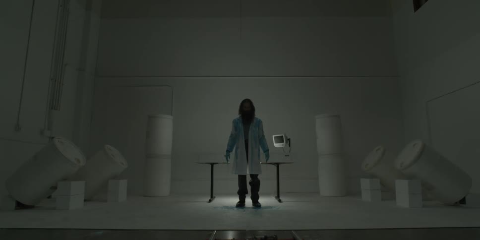 Man in a lab coat stands next to a table