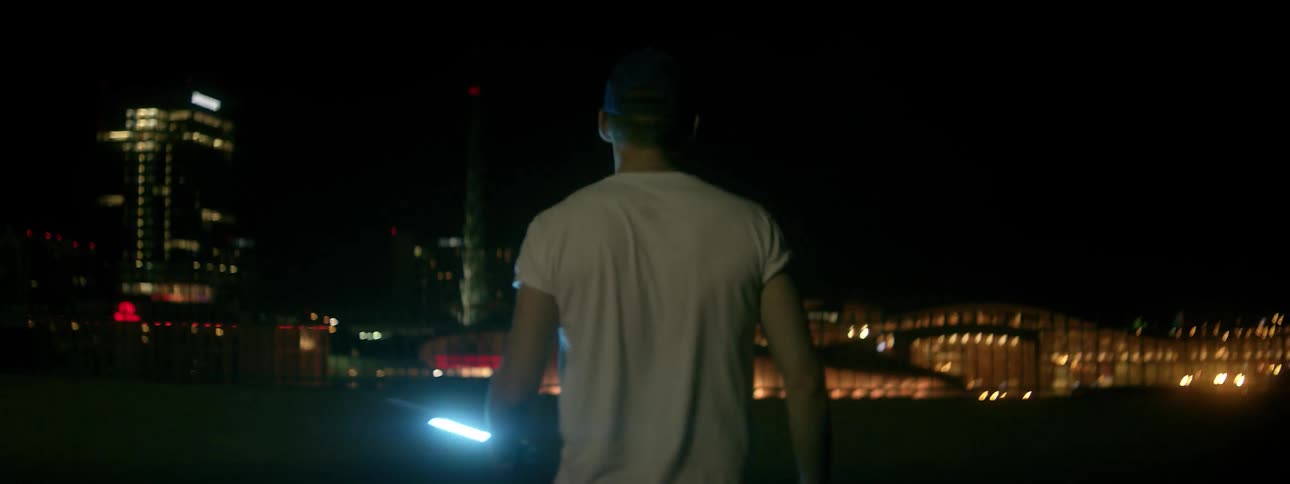 Man holding a light walks outside in a city at night