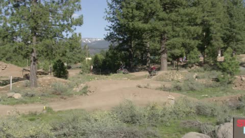 Boys race off road bikes on a course in a natural setting