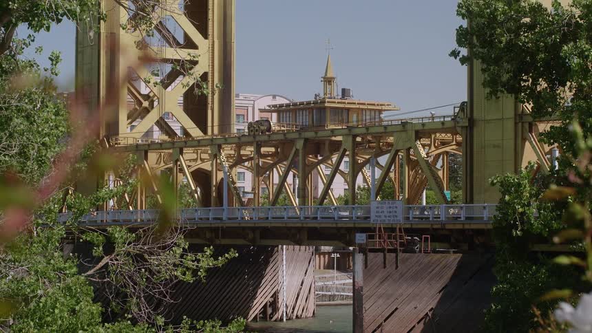 Cars and people travel across a bridge on a sunny day