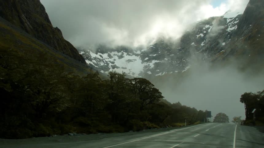 Fog covers the foot of a snowy mountain