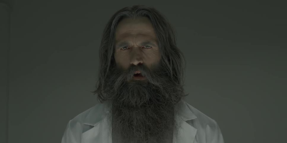 A bearded man stares in a gray room