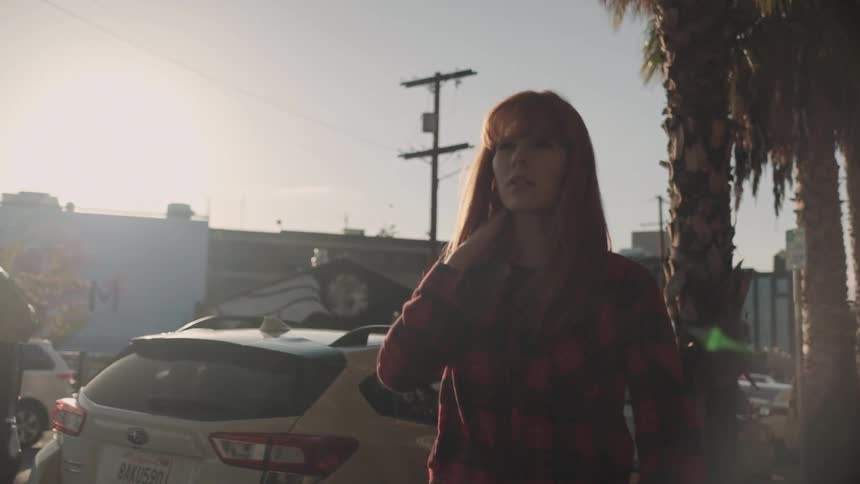 A red haired woman walks outside in the city