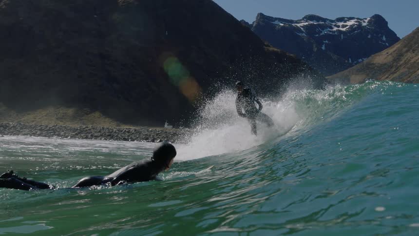 A man in a wet suit rides a wave towards the shore