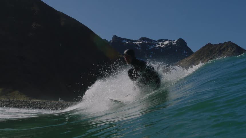 A surfer rides a tall wave near the shore