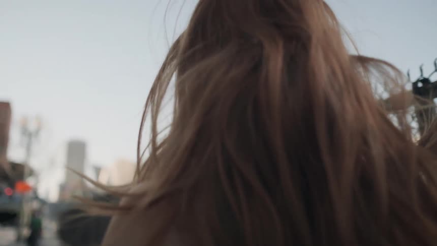 A red haired woman throws her hair while walking