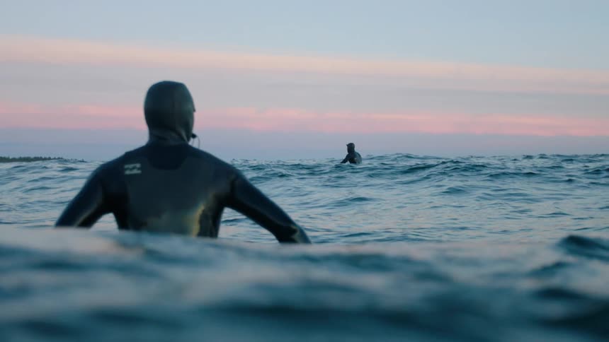 Men in wet suits float in the ocean