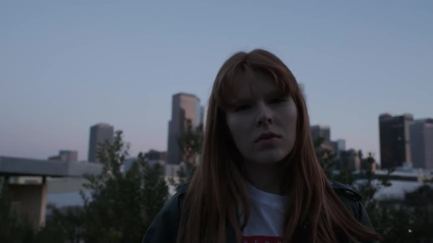 A red haired woman stands outside