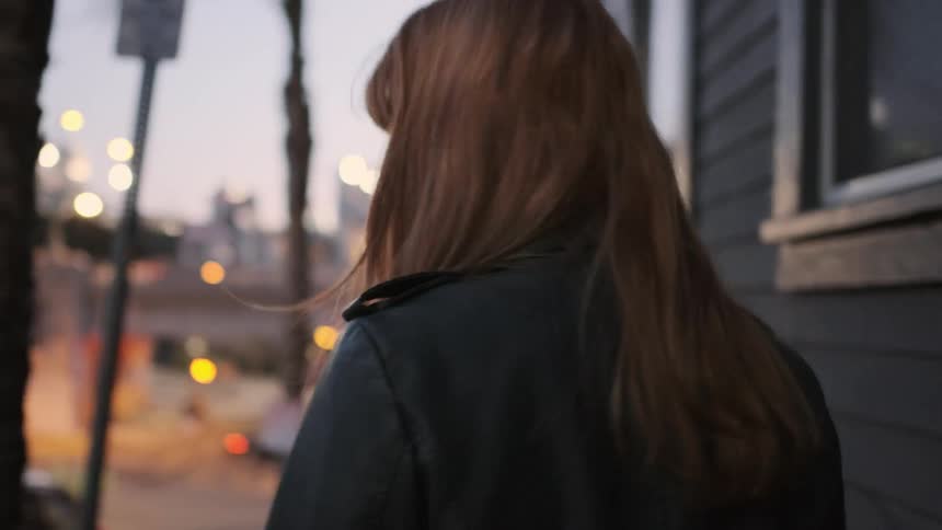 A red haired woman walks on a city sidewalk
