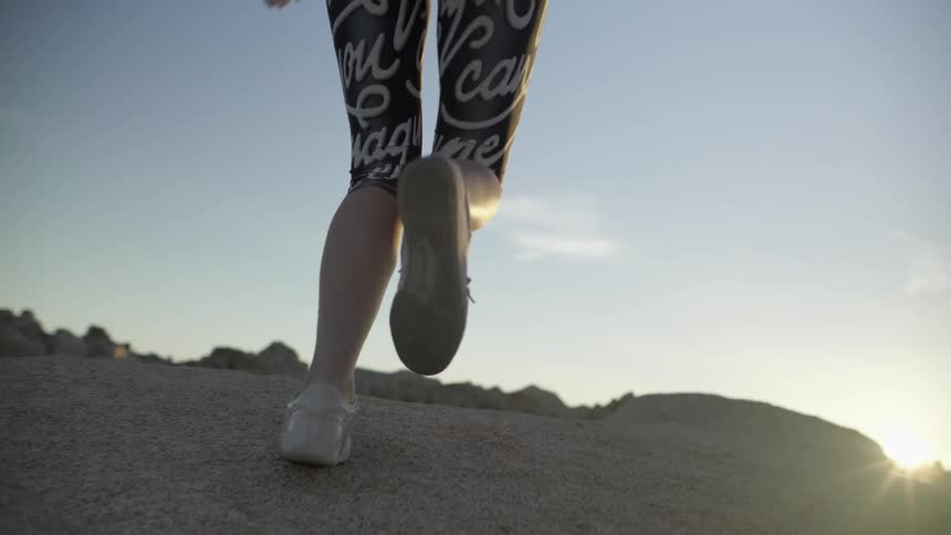 A woman jogs happily up a rock