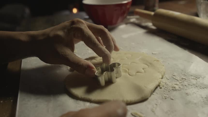 A person cuts dough to form cookies