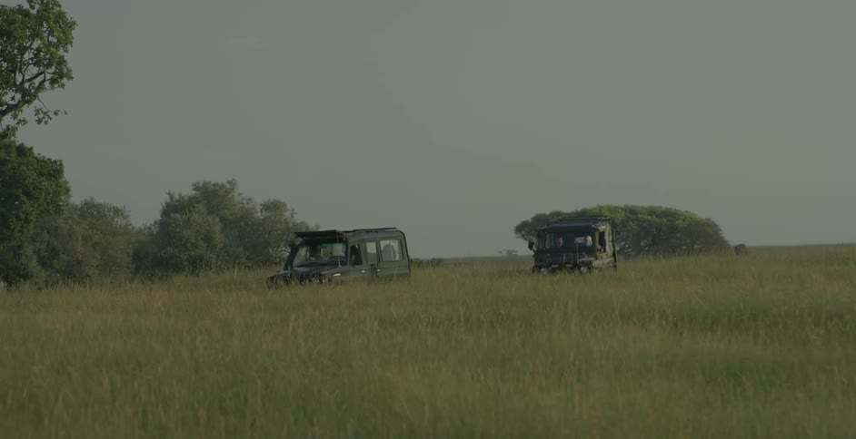 Two trucks travel in a field
