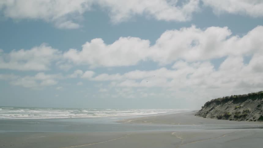 Waves roll onto the shore of a beach on a cloudy day