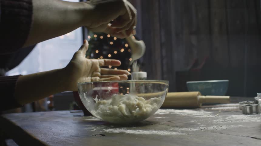 Person cooking with christmas tree behind table