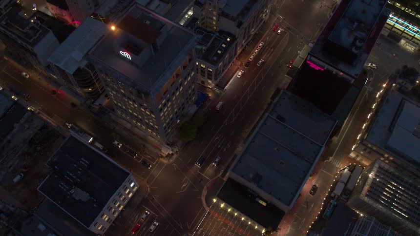Vehicles are traveling through a city intersection at night