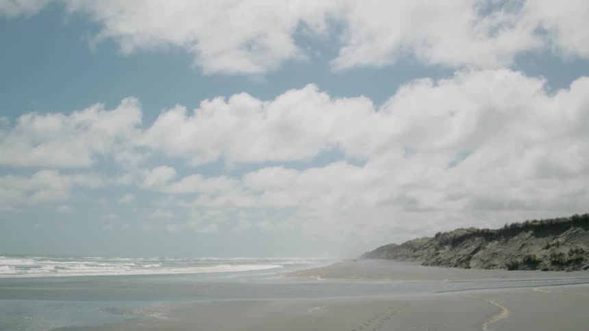 Waves roll toward a beach on a cloudy day