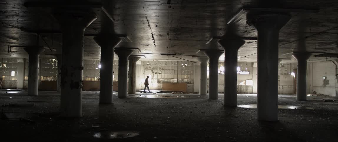 Water falls through a floor and pools as a man walks by