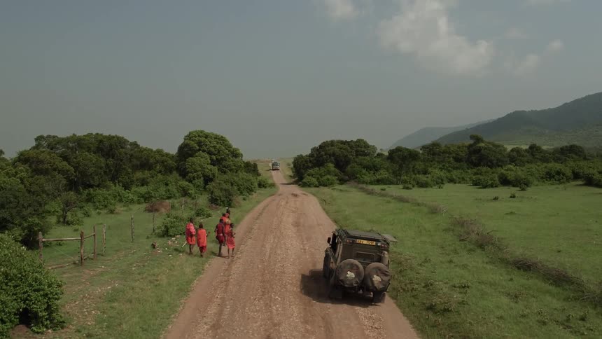 Trucks drive down a dirt road