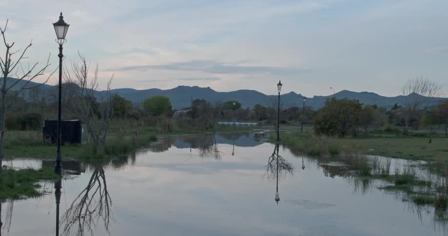 A bird flies away from a flooded public park at dawn