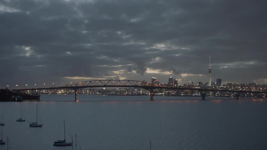 Boats float in the water near a city bridge