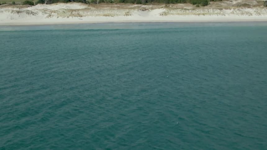 The coast is empty besides waves crashing on the sand