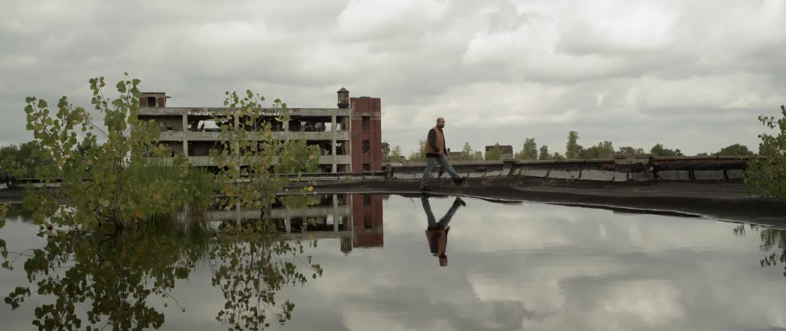 A man is walking near a puddle on a cloudy day