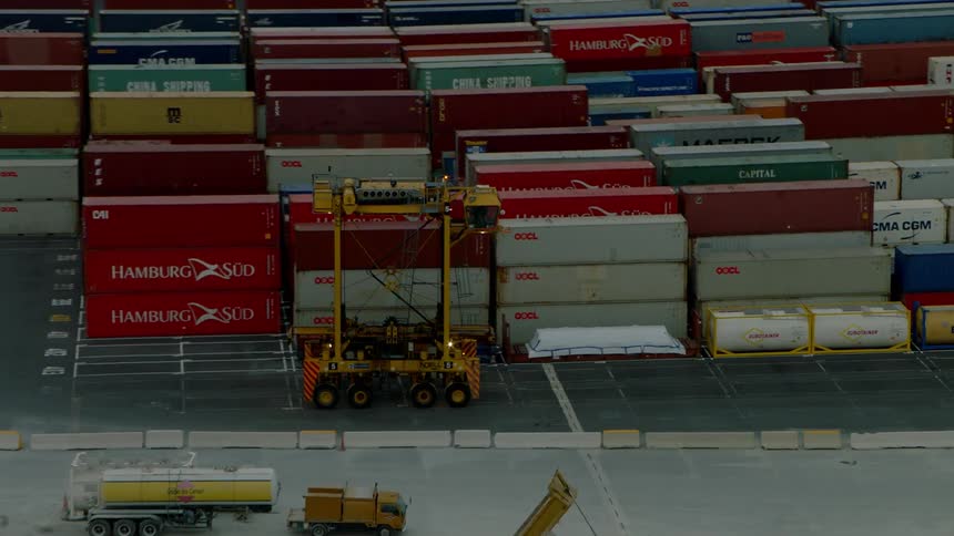 Transport vehicles travel on a dock with shipping containers