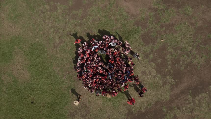 A group of school children gather in a field