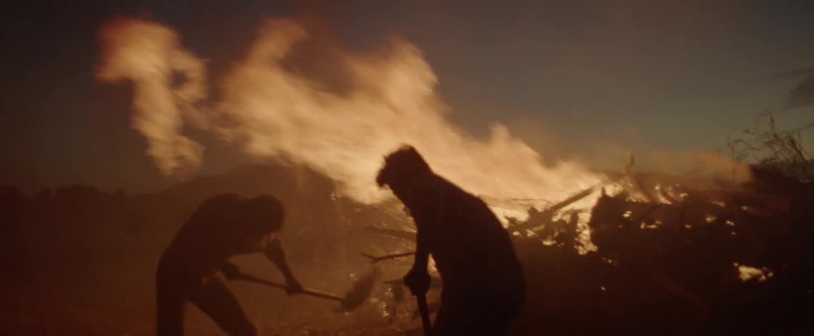 Men shovel dirt onto a fire