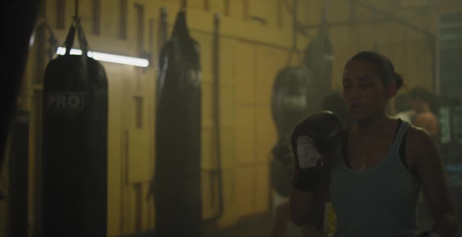 A female fighter is kicking a punching bag in a gym