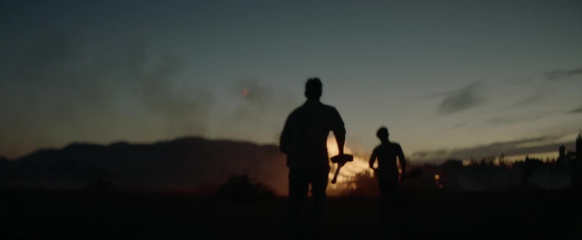People are running around a large fire at night with shovels