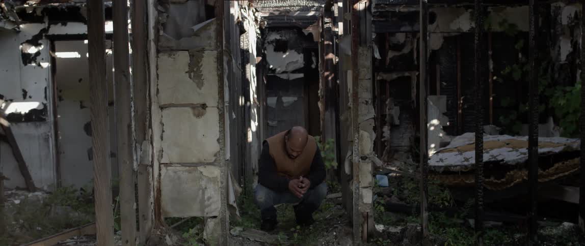 A man kneels inside an abandoned house
