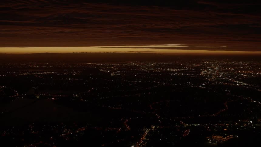 The sun sets beyond a large city