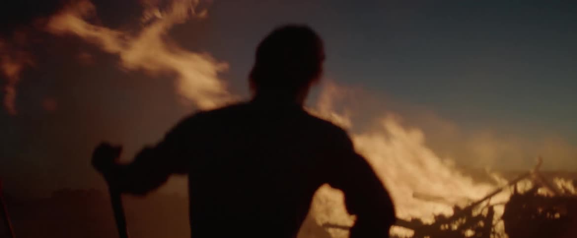 Man stands with shovel next to a large fire
