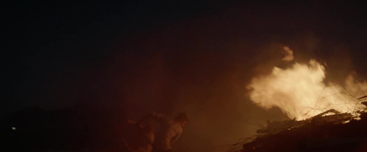 People dancing by a fire at night