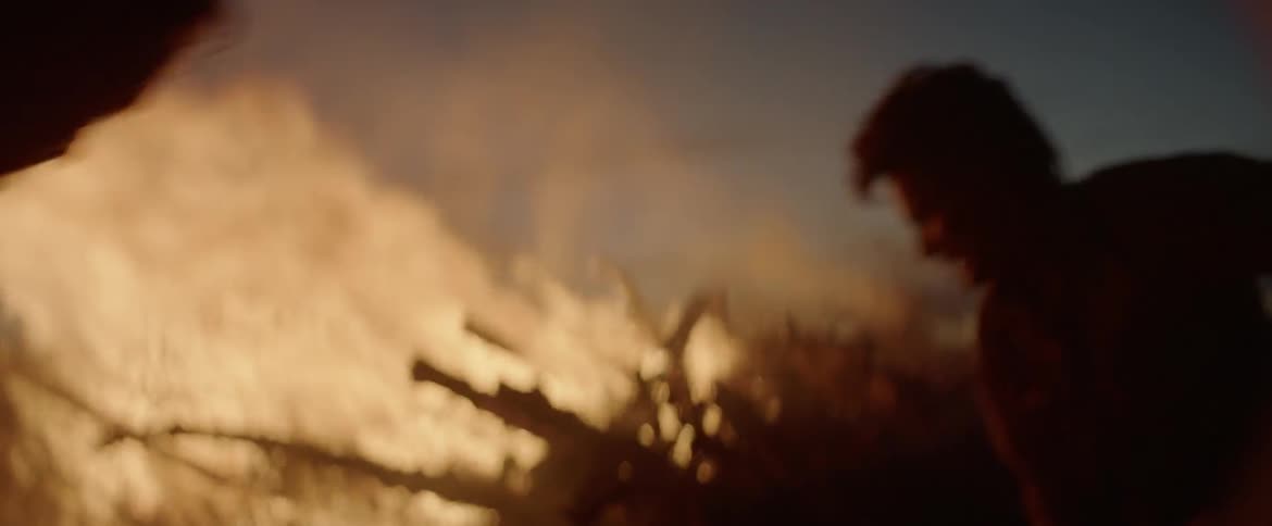 A man is furiously throwing dirt onto a large fire