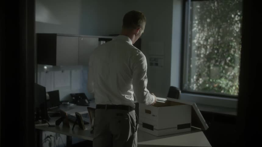 A man packs up an office into boxes